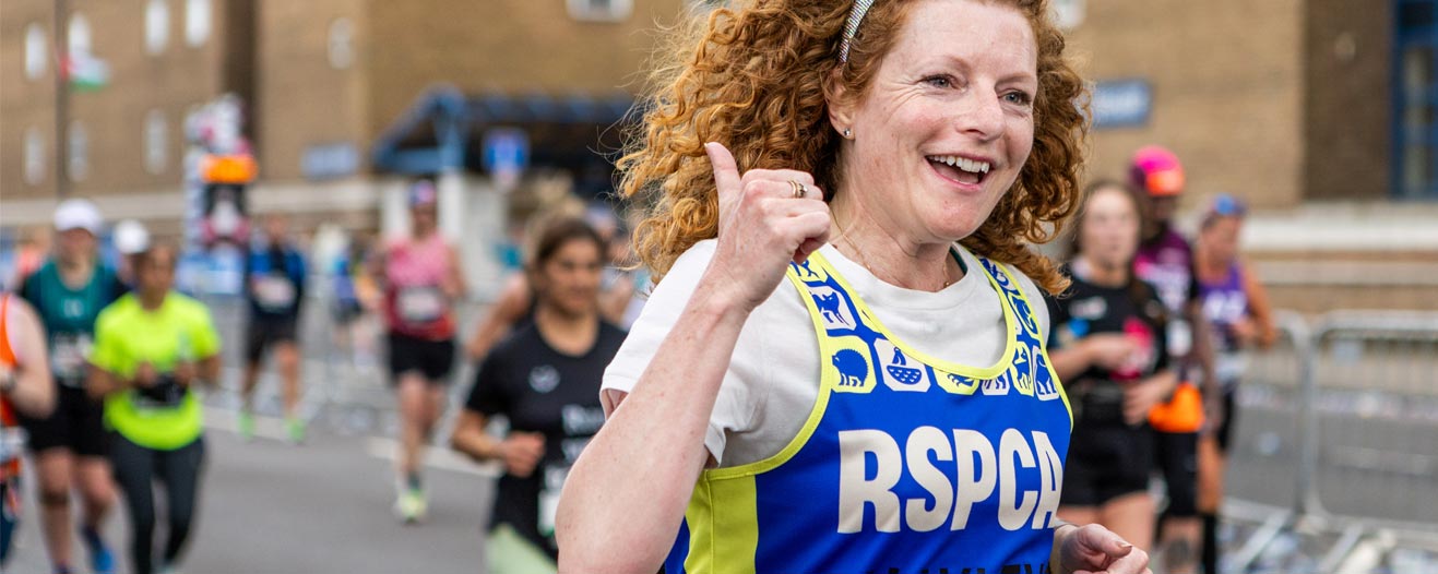 An RSPCA fundraiser giving a thumbs up during a running event.